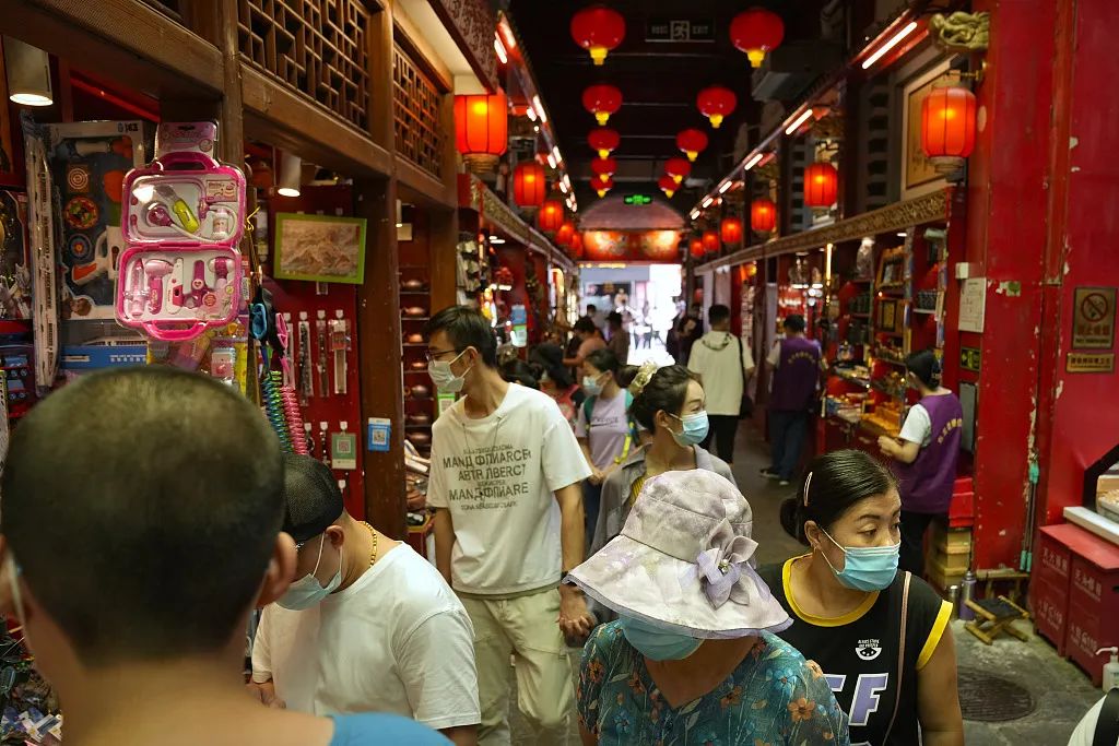 戴着口罩的游客正在游览纪念品商店。图/视觉中国